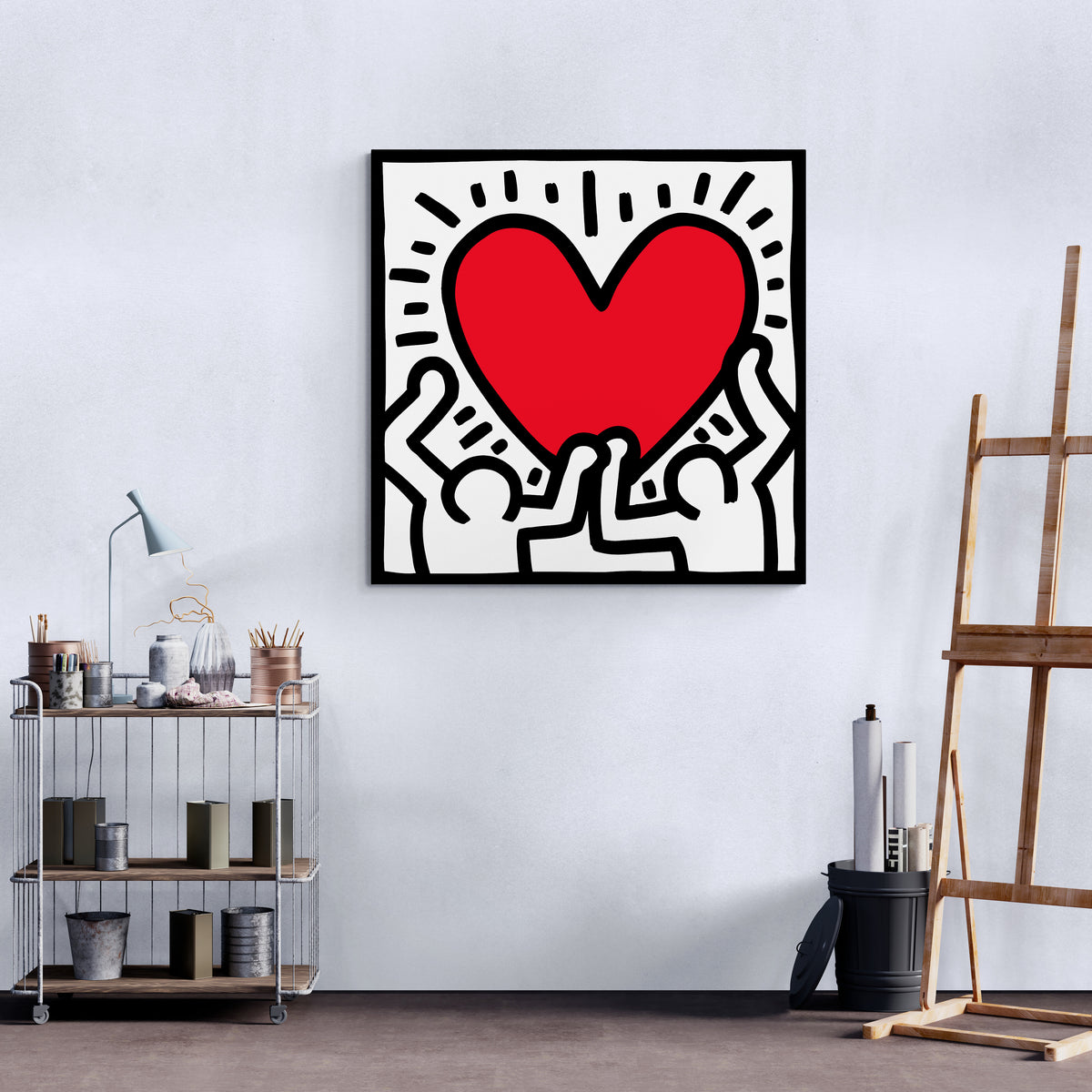 Tableau Coeur de Keith Haring : Œuvre d'art en forme de cœur rouge vif, deux personnages soulevant joyeusement le cœur, lignes noires audacieuses, fond blanc.